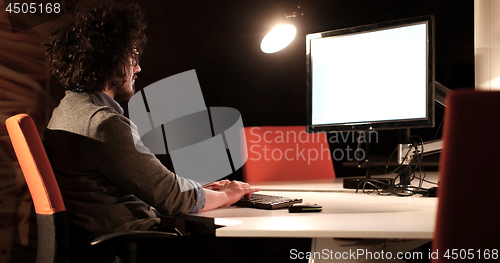 Image of man working on computer in dark office