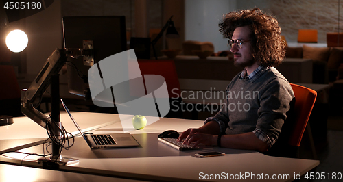 Image of man working on computer in dark office