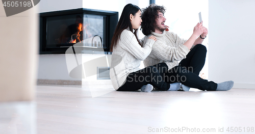 Image of Young Couple using digital tablet on the floor