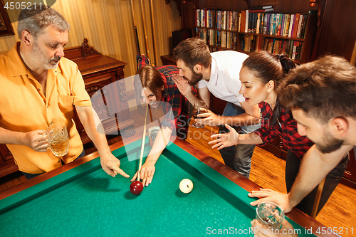 Image of Young men and women playing billiards at office after work.