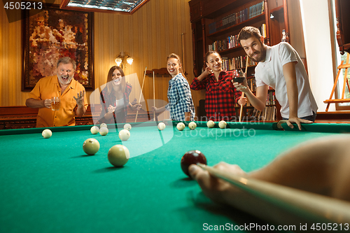 Image of Young men and women playing billiards at office after work.