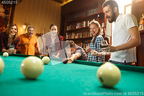 Image of Young men and women playing billiards at office after work.