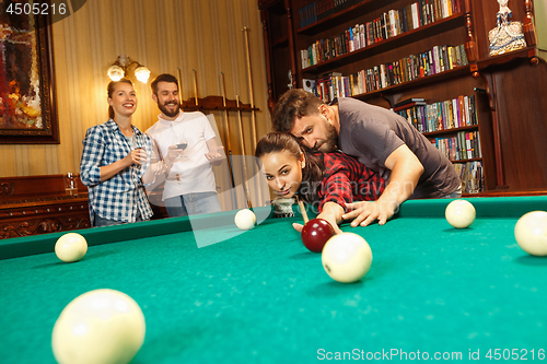 Image of Young men and women playing billiards at office after work.