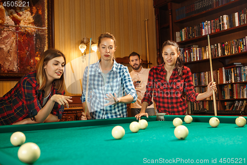 Image of Young men and women playing billiards at office after work.