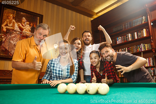 Image of Young men and women playing billiards at office after work.