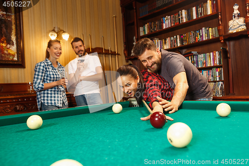 Image of Young men and women playing billiards at office after work.