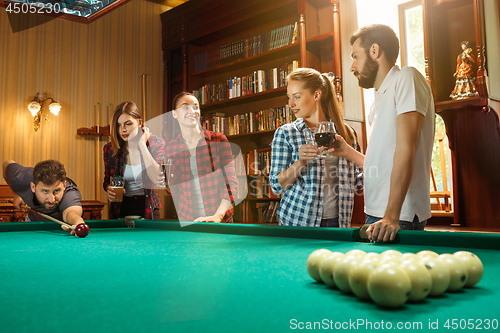 Image of Young men and women playing billiards at office after work.