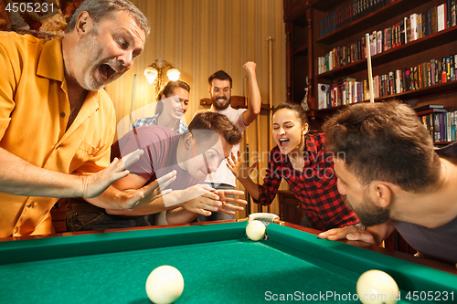 Image of Young men and women playing billiards at office after work.