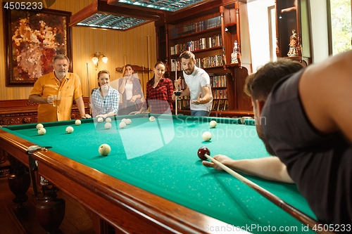 Image of Young men and women playing billiards at office after work.