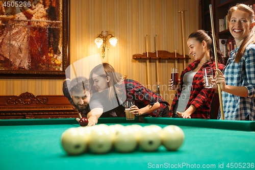 Image of Young men and women playing billiards at office after work.