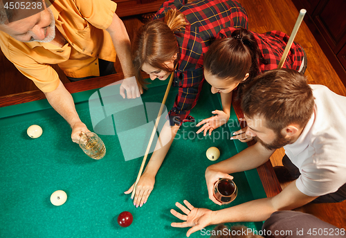 Image of Young men and women playing billiards at office after work.