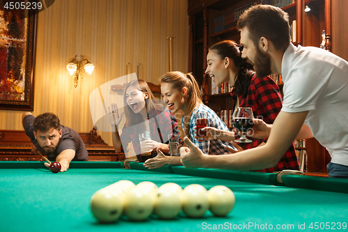 Image of Young men and women playing billiards at office after work.