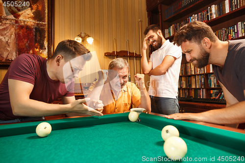 Image of The displeased men playing billiards at office after work.