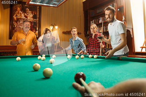 Image of Young men and women playing billiards at office after work.