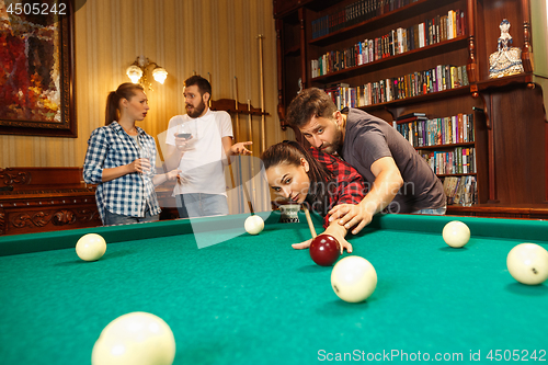 Image of Young men and women playing billiards at office after work.