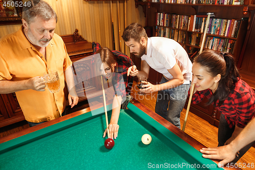 Image of Young men and women playing billiards at office after work.