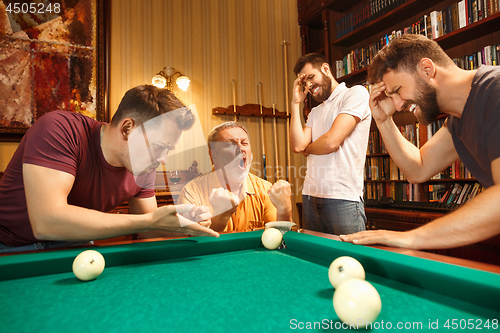 Image of The displeased men playing billiards at office after work.