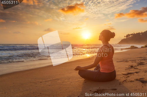 Image of Woman doing yoga oudoors at beach - Padmasana lotus pose