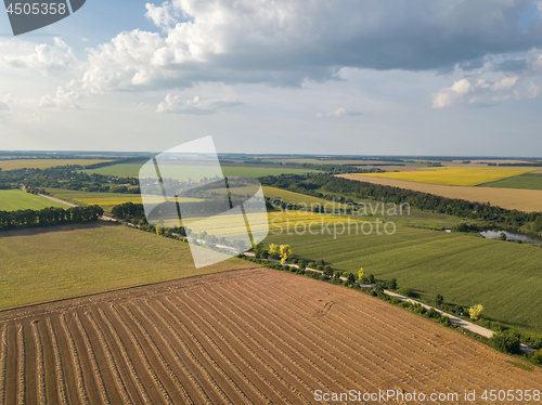 Image of Summer countryside landscape with agricultural fields with organic crops and after harvesting against blue cloudy sky. Aerial view from drone.