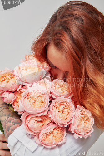 Image of pretty girl holding a bouquet of pink roses