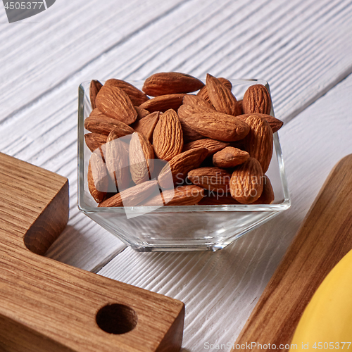 Image of Close-up of almond nuts in a glass bowl on a wooden board on a gray wooden background. Vegetable protein for vegans.