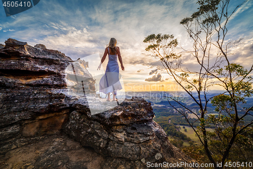 Image of Standing on a rock  with dress blowing in the wind she dreams