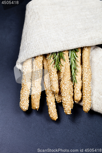 Image of Italian grissini or salted bread sticks on linen napkin on black