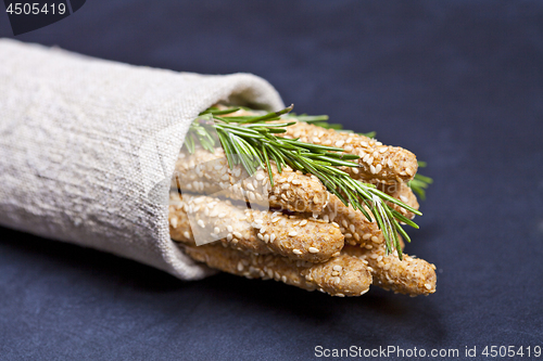 Image of Italian grissini or salted bread sticks with rosemary herb on li