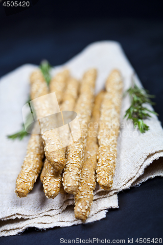 Image of Italian grissini or salted bread sticks on linen napkin on black