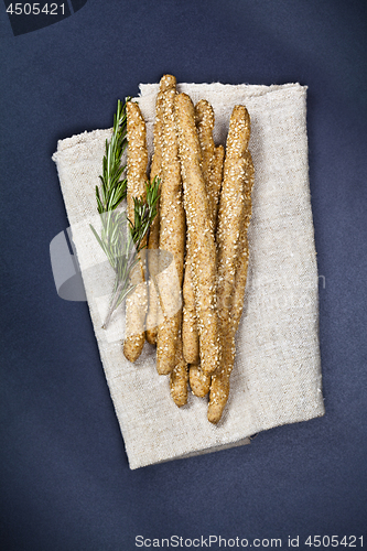 Image of Italian grissini or salted bread sticks on linen napkin on black