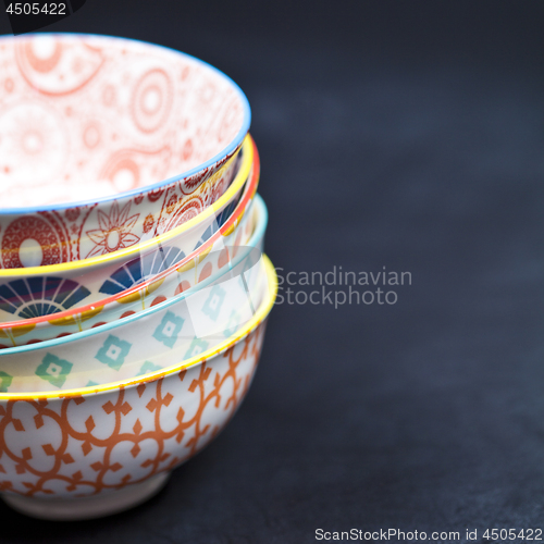 Image of Stack of colorful empty ceramic bowls closeup on black board bac