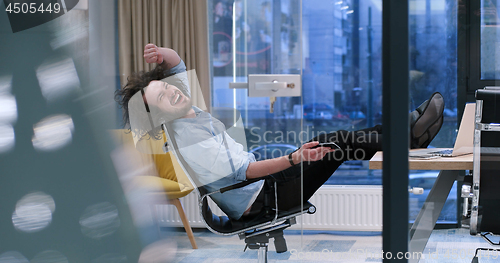Image of businessman sitting with legs on desk