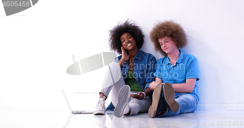 Image of multiethnic couple sitting on the floor using a laptop and table