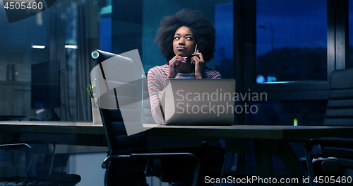 Image of black businesswoman using a laptop in night startup office