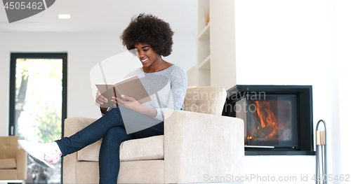 Image of black woman at home reading book