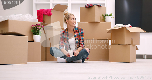 Image of woman with many cardboard boxes sitting on floor