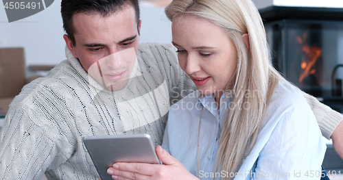 Image of Young Couple using digital tablet on the floor