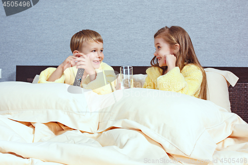 Image of Happy laughing kids, boy and girl in soft bathrobe after bath play on white bed