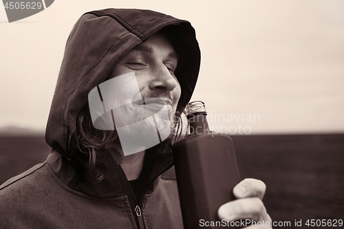 Image of Hooded man drinking spirits in Iceland