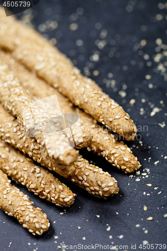 Image of Italian grissini or salted bread sticks on linen napkin on black