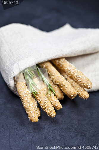 Image of Italian grissini or salted bread sticks with rosemary herb on li