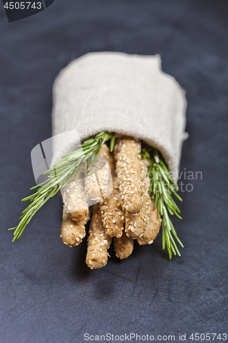 Image of Italian grissini or salted bread sticks with rosemary herb on li