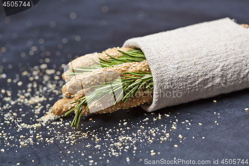 Image of Italian grissini or salted bread sticks with rosemary herb on li