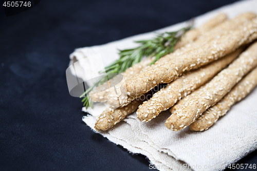 Image of Italian grissini or salted bread sticks with rosemary herb on li