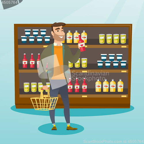 Image of Man holding shopping basket and bottle of sauce.