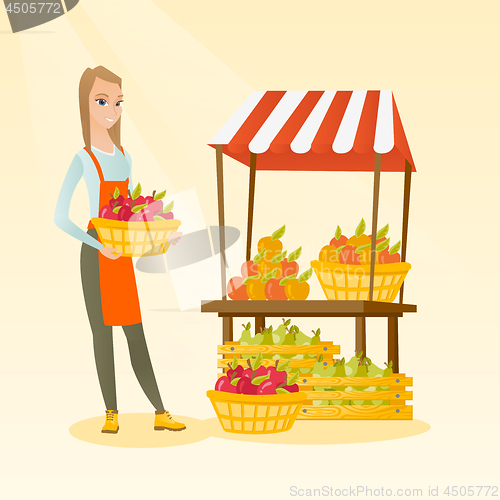 Image of Greengrocer holding box full of apples.