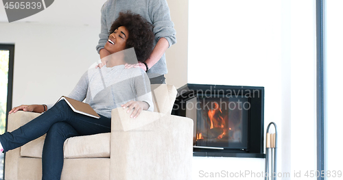 Image of multiethnic couple hugging in front of fireplace