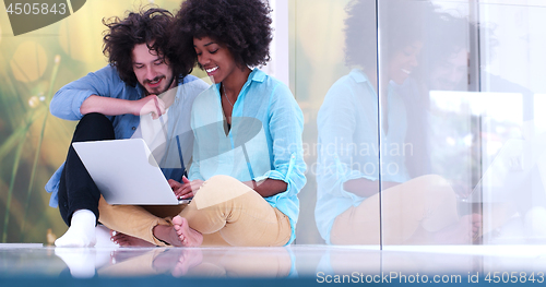 Image of multiethnic couple using a laptop on the floor