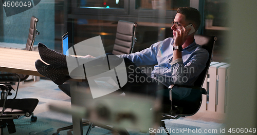 Image of businessman sitting with legs on desk at office