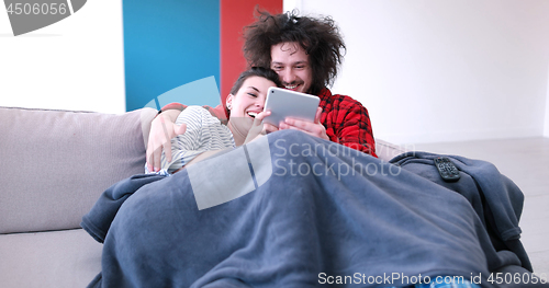 Image of couple relaxing at  home with tablet computers